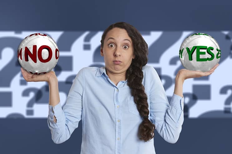 Confused woman holding up balls with yes on one ball and no on the other.