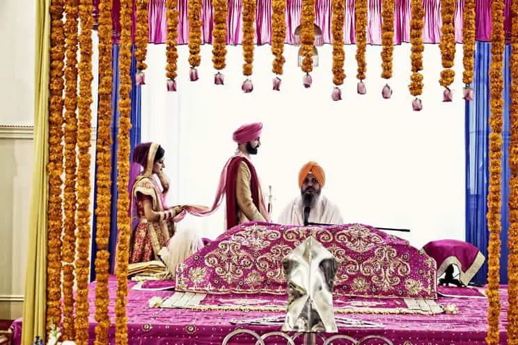 Sikh groom and bride walking around the holy book during a Sikh wedding