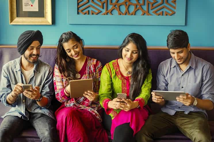 Sikhs and Hindu men and women sitting together browsing on phones and tablets